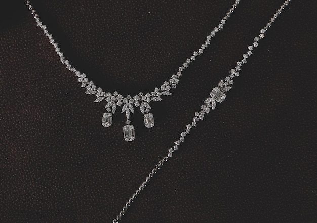 A stunning diamond necklace with intricate floral designs and dangling marquise-cut stones, set against a dark background.