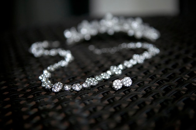 A delicate necklace with sparkling gemstones rests on a textured black surface.