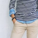 Person wearing a navy and white striped shirt with beige pants, hands in pockets.