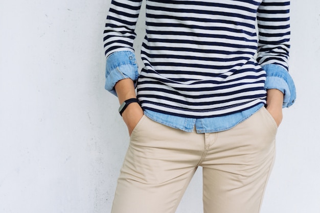 Person wearing a navy and white striped shirt with beige pants, hands in pockets.