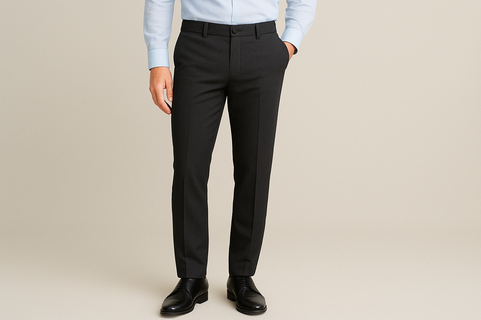 Man wearing black stretchable formal pants paired with a light blue shirt and black dress shoes against a plain background.