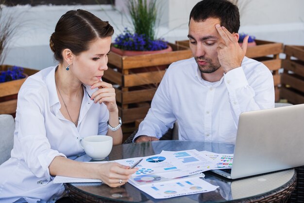 Tired young professional working at a computer in a cafe, looking stressed while resting their head on the desk today.